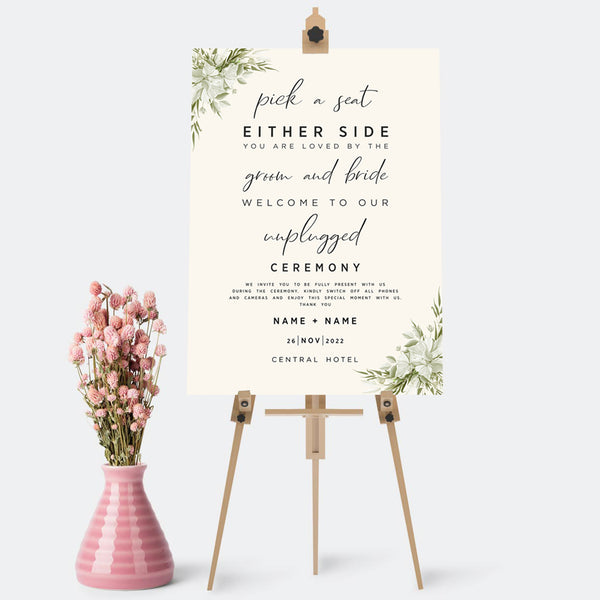 Wedding Ceremony sign which tells the guests where to sit "pick a seat either side" and to turn of phones and cameras "unplugged Ceremony", it is personalised with names, date and venue. Sizes come in A1,A2 and A3. It has a cream background with pale flowers and greenery in two opposite corners.