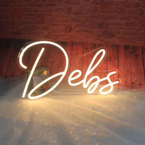 The image shows a custom LED neon sign spelling out the name "Debs." These types of signs are popular for various uses, including home decor, retail shop props and social events.